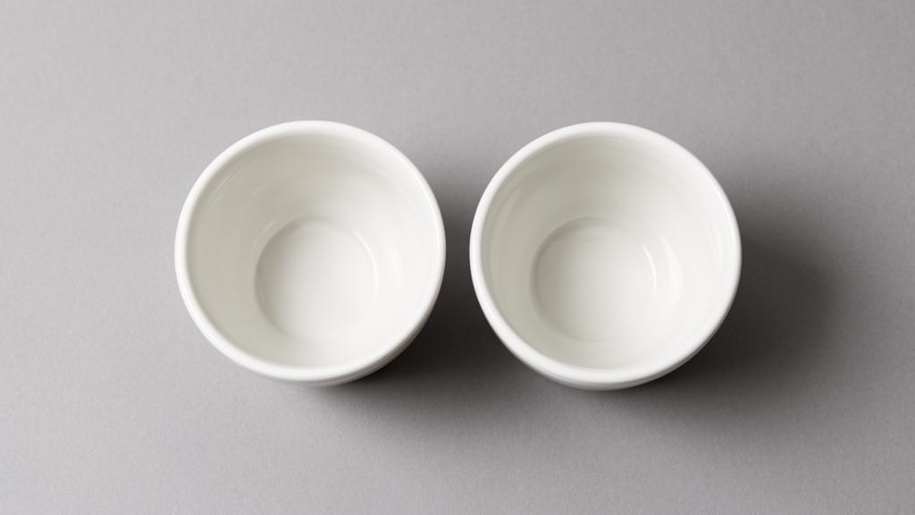 Two identical white cups side by side on a grey surface